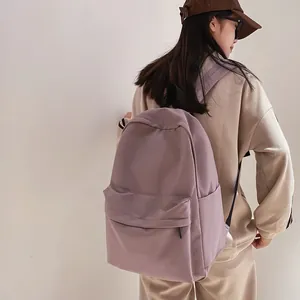 Minimalist purple waterproof nylon backpack for students shown from a side view on a model