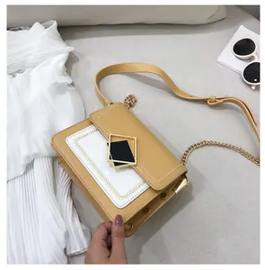 Détail du sac à bandoulière en cuir jaune moutarde et blanc avec boucle noire chic