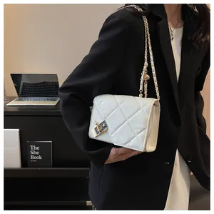 Close-up of white quilted crossbody bag with gold chain strap and luxury buckle detail