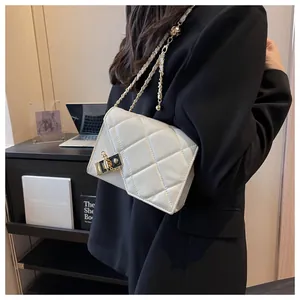 Detail of elegant quilted crossbody bag featuring gold chain strap and metal lock closure