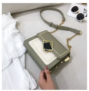 Détail du sac à main en cuir bicolore avec boucle métallique géométrique et bandoulière