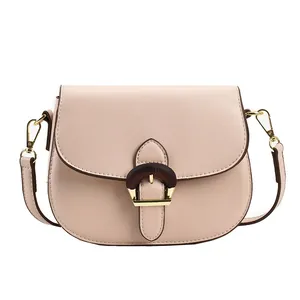 Pale pink saddle bag with horseshoe buckle and gold hardware on white background