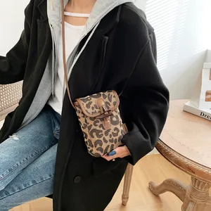 Close-up of leopard print mini crossbody bag with leather trim and horn buckle detail