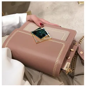 Détail de la broderie de blé et du fermoir doré sur un sac beige et rose