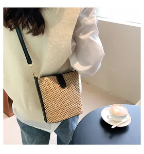 Detail of a woven straw bag featuring a black leather strap and buckle in a cafe setting