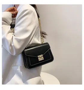 Detalle del bolso bandolera negro con cierre de giro dorado y pespuntes en blanco