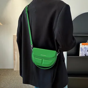 Grüne Crossbody Satteltasche aus Leder mit Gravur auf einem stilvollen Modell