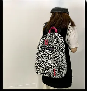Détail du sac à dos léopard avec poignée rose et écusson logo porté par un mannequin