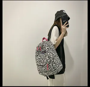 Détail d'un sac à dos en toile léopard avec poignée rose et étiquette tissée de marque