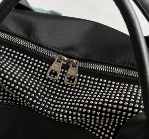 Détail de la double fermeture éclair argentée et des rivets en strass sur le sac noir
