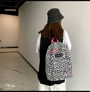 Détail du sac à dos en toile léopard avec fermetures éclair et poignée rose vif contrastées