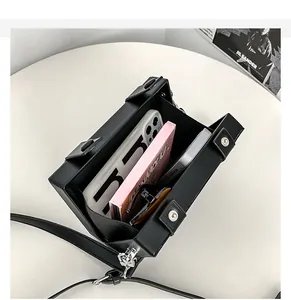 Internal view of black square box bag showing capacity for phone and sunglasses