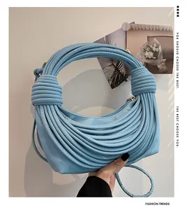Détail du sac croissant bleu clair avec design noué et fermeture éclair en métal lisse