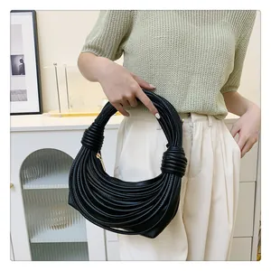Détail du sac croissant noir plissé avec poignée à nœud et finition texturée lisse