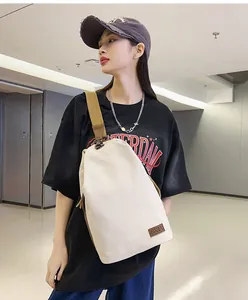 Détail du sac à bandoulière en toile blanc cassé avec sangle large brune et logo NANA