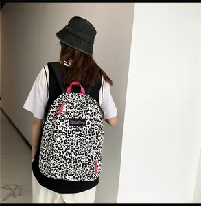 Vue arrière d'un sac à dos en toile léopard avec fermetures éclair roses sur modèle