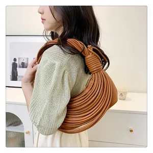 Détail du sac à bandoulière tressé marron montrant le nœud et la fermeture dorée