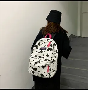 Détail du sac à dos en toile à motif vache avec poignée et fermetures éclair rose vif