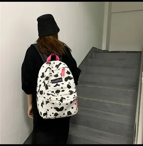 Détail d'un sac à dos en toile à motif vache avec accents roses et étiquette tissée