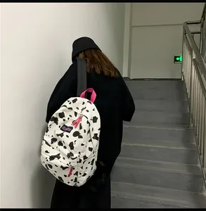 Détail du sac à dos en toile à motif vache avec poignée magenta et étiquette bleue
