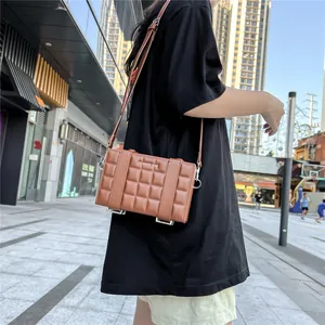 Detail of a brown quilted leather crossbody bag with silver lettering and adjustable strap