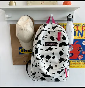 Détail d'un sac à dos en toile à motif vache avec poignée rose et étiquette de marque