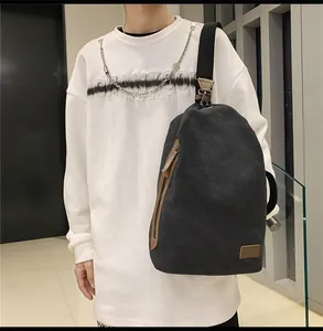 Dettaglio borsa a tracolla in tela nera con tiranti in pelle marrone ed etichetta minimalista
