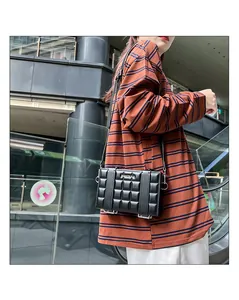 Close-up of black box bag with textured grid pattern and metallic strap buckles