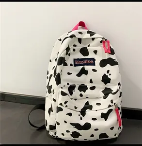 Détail du sac à dos en toile à motif vache avec sangles roses et écusson brodé