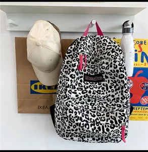 Détail d'un sac à dos en toile léopard avec bordure en nylon rose et poche zippée