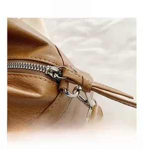 Close-up of smooth silver zipper and lychee textured brown leather on a tote bag