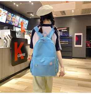 Close-up back view of a student wearing a sky blue canvas backpack in a cafe