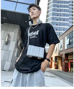Silver quilted box bag shown on shoulder in a modern urban street setting for men