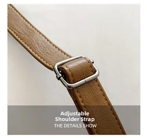 Detail of adjustable brown pebble leather shoulder strap with silver buckle and fine stitching
