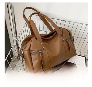 Detail of brown leather tote bag with tassel zippers and rivets in a shopping basket