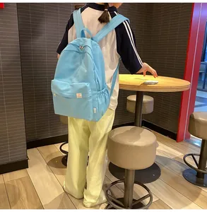 Sky blue nylon backpack with DIFA label and cartoon bear patch shown on a model