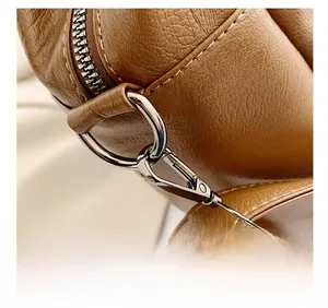 Detailed close-up of brown litchi grain leather texture and silver metal hook buckle