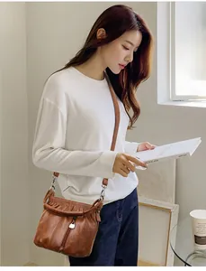 Sac bandoulière marron avec fermeture plissée et poche zippée porté par un mannequin