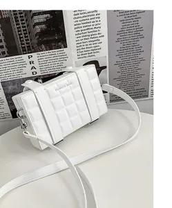 Close-up of white quilted mini box bag with FILWHITE text on stylish newspaper background