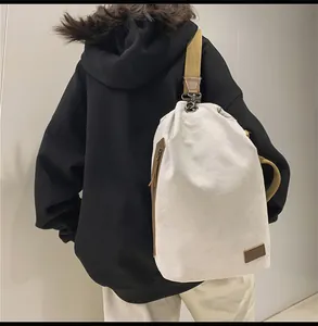 Dettaglio della borsa a secchiello in tela crema con finiture in pelle marrone