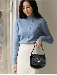 Détail d'un sac à main en cuir souple noir avec texture plissée et pompon décoratif