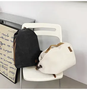Détail de sacs à bandoulière en toile noir et beige avec poignées et logo en cuir rétro