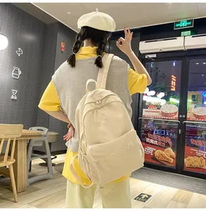 Rear view of a minimalist beige canvas backpack with large front pocket for school