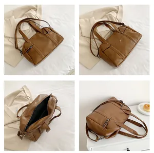 Detail view of brown leather Boston bag showing dual handles and interior pockets