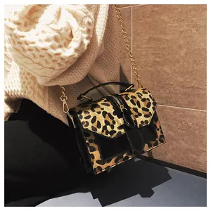 Detalle de bolso bandolera de leopardo con cadena dorada y adornos en negro liso