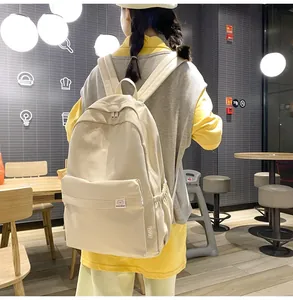 Macro detail of cream canvas backpack featuring the front pocket and brand label
