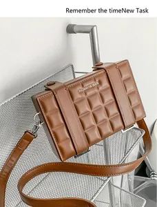 Detailed macro of the brown quilted leather box bag with embossed grid pattern and logo