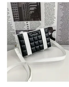 Detail of a square crossbody bag with black quilted leather and white branding strap