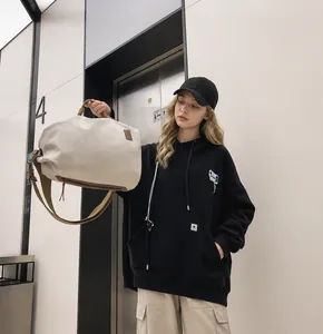 Dettaglio della borsa tote in tela bianco sporco con manici marroni e cerniera in metallo