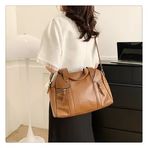 Brown faux leather tote bag with dual handles and crossbody strap worn by a model